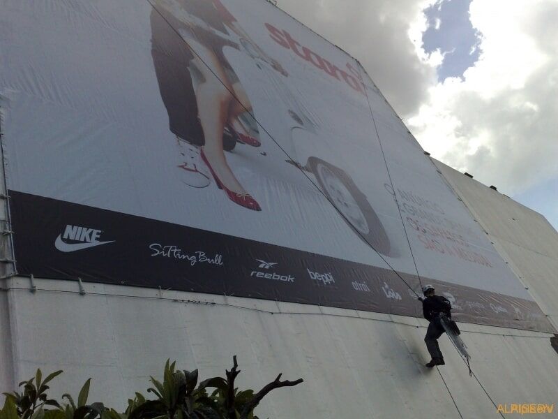 Um homem está escalando um grande outdoor da Nike