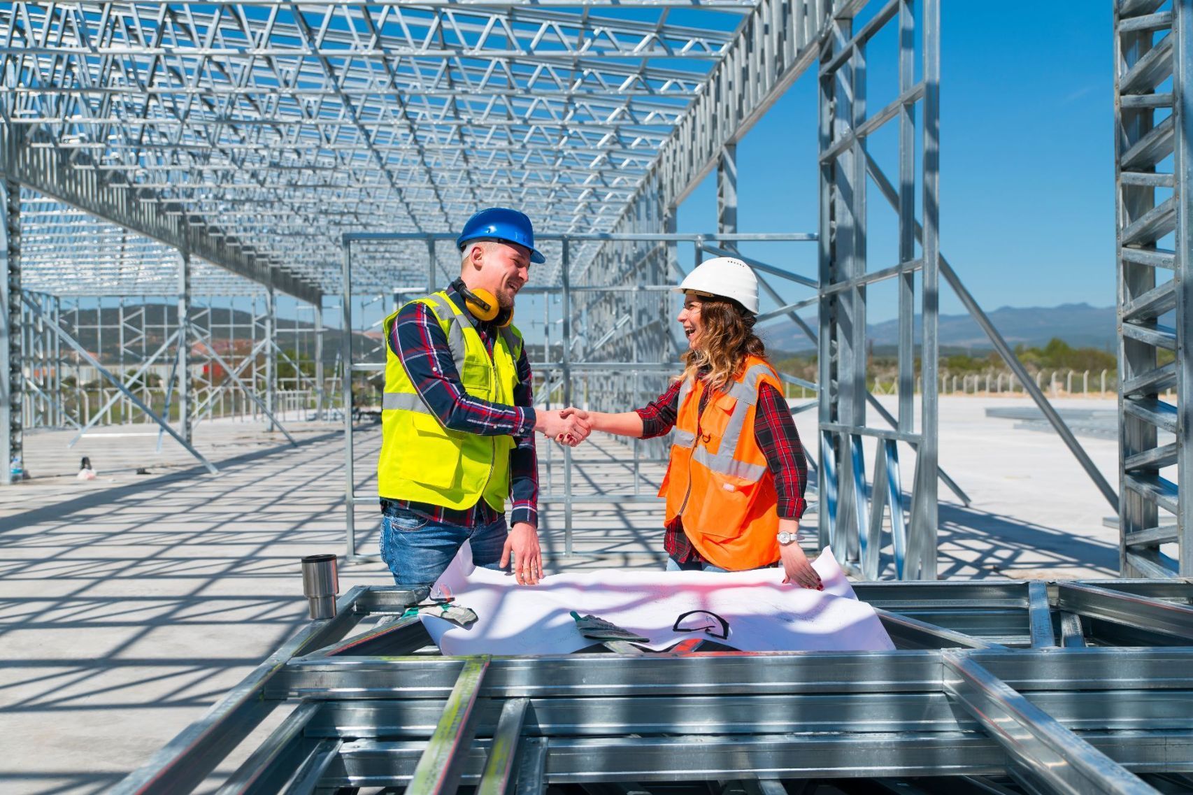 Bauplanbesprechung auf Baustelle Mann und Frau mit Warnweste und Helm