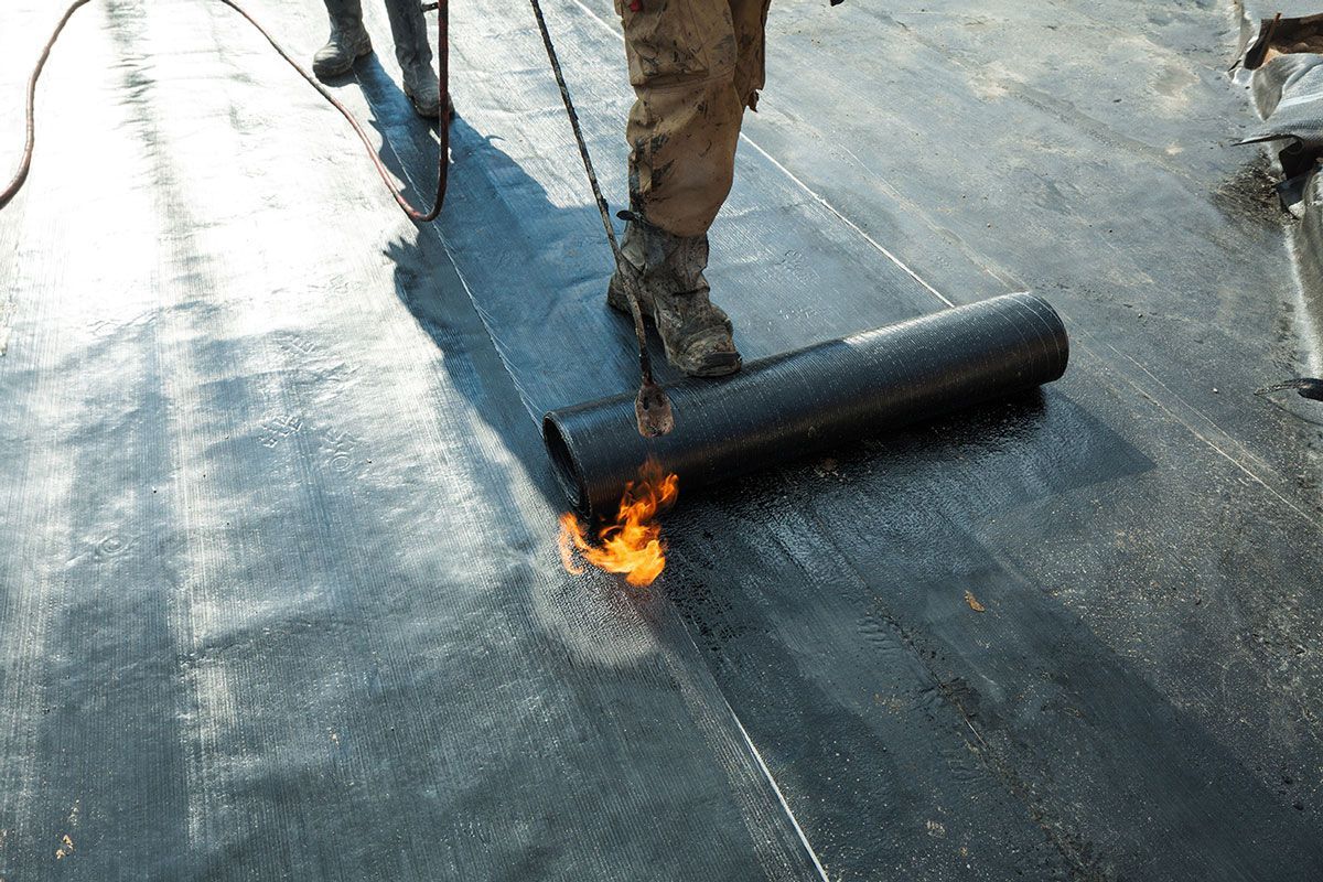 Ouvrier qui installe une membrane EPDM sur un toit plat