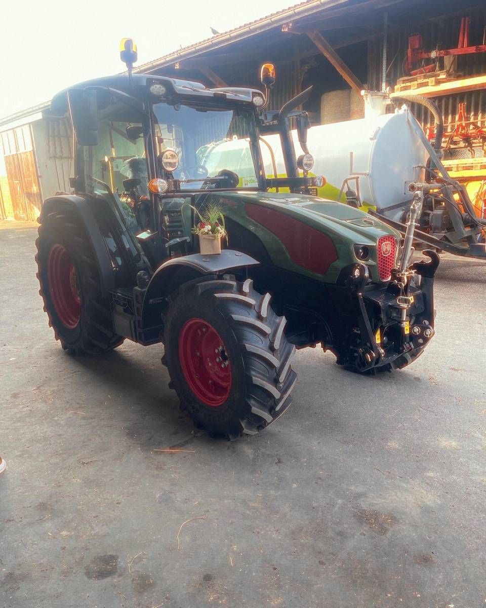 Grün-roter Traktor, der in einer Werkstatt parkt, Ansicht von vorne links.