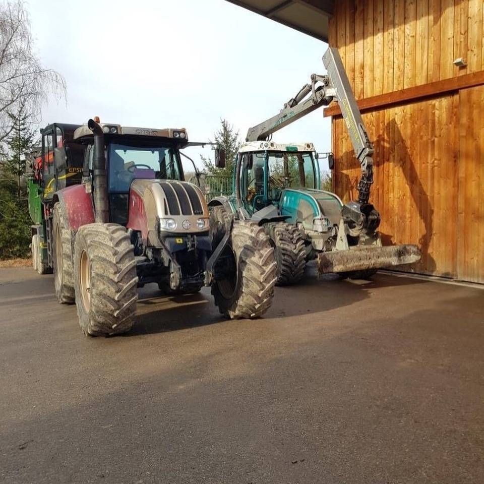 Zwei Traktoren parkten neben einer Holzscheune, einer davon mit einem Frontlader.