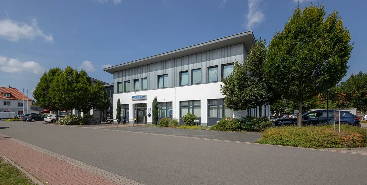 Ein großes weißes Gebäude mit vielen Fenstern und Bäumen davor.