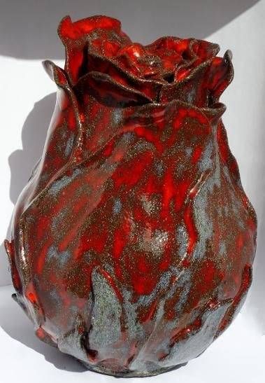 Rote und schwarze, strukturierte Keramikvase mit gerüschter Öffnung vor weissem Hintergrund