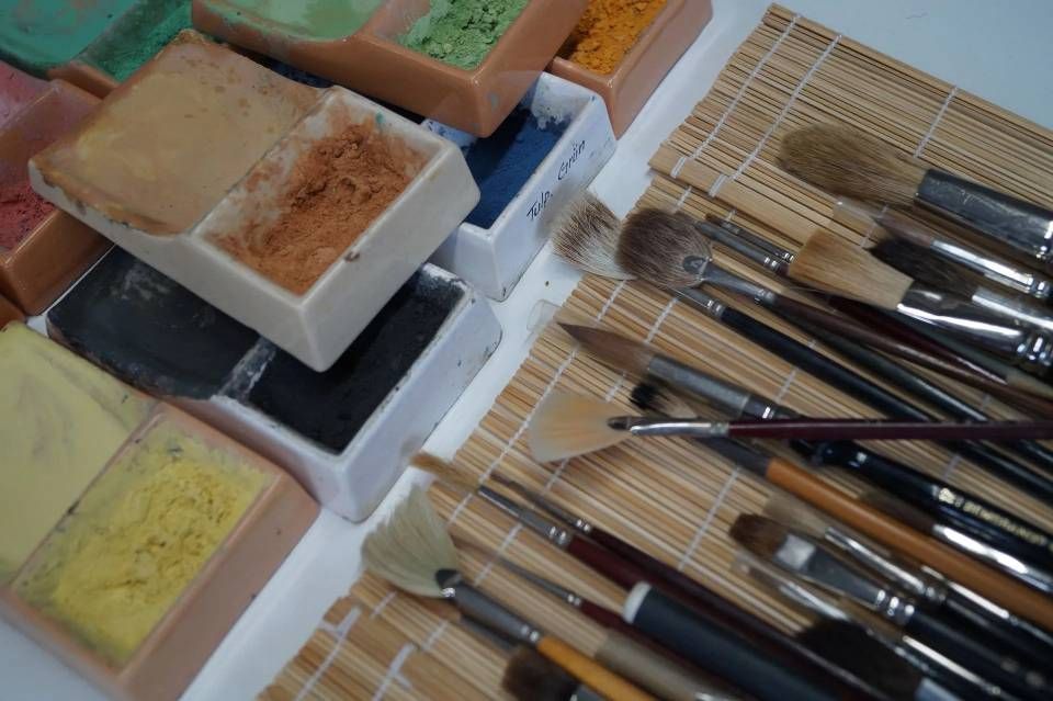 Pinsel und Pastellkreiden sind auf einem Tisch für Kunst- oder Malarbeiten angeordnet.