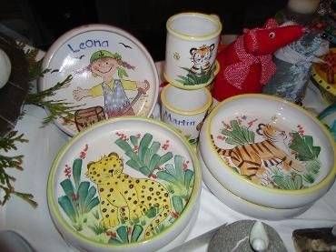 Bunte Kindergerichte mit Tier- und Gartenmotiven sind auf einem Tisch arrangiert.