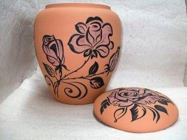 Orangefarbener Keramikbehälter und passender Deckel mit schwarzen floralen Rankenmotiven auf weissem Hintergrund