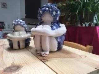 Zwei kleine Figuren mit blau-weissem Haar sitzen auf einem Holztisch im Haus.