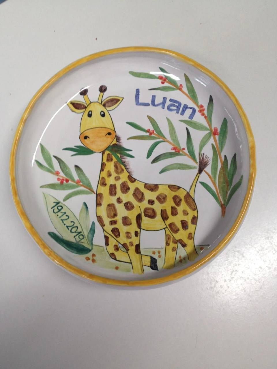 Runder Teller mit einer Comic-Giraffe, grünen Blättern und dem Namen „Luan“ in blauer Schrift.