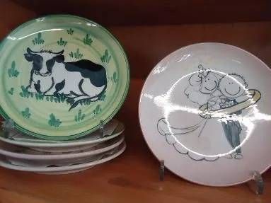 Ein Stapel grüner Teller mit Katzenmotiven neben einem weissen Teller mit einer skizzierten Cartoon-Katze