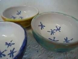 Drei kleine Keramikschalen mit blauen Blumenmustern und farbigen Rändern auf grauem Untergrund
