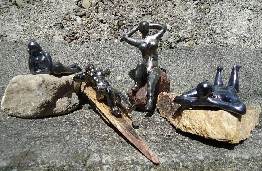 Kleine, dunkle Figuren posierten im Freien auf Felsen, eine lag, die andere stand mit erhobenen Armen.