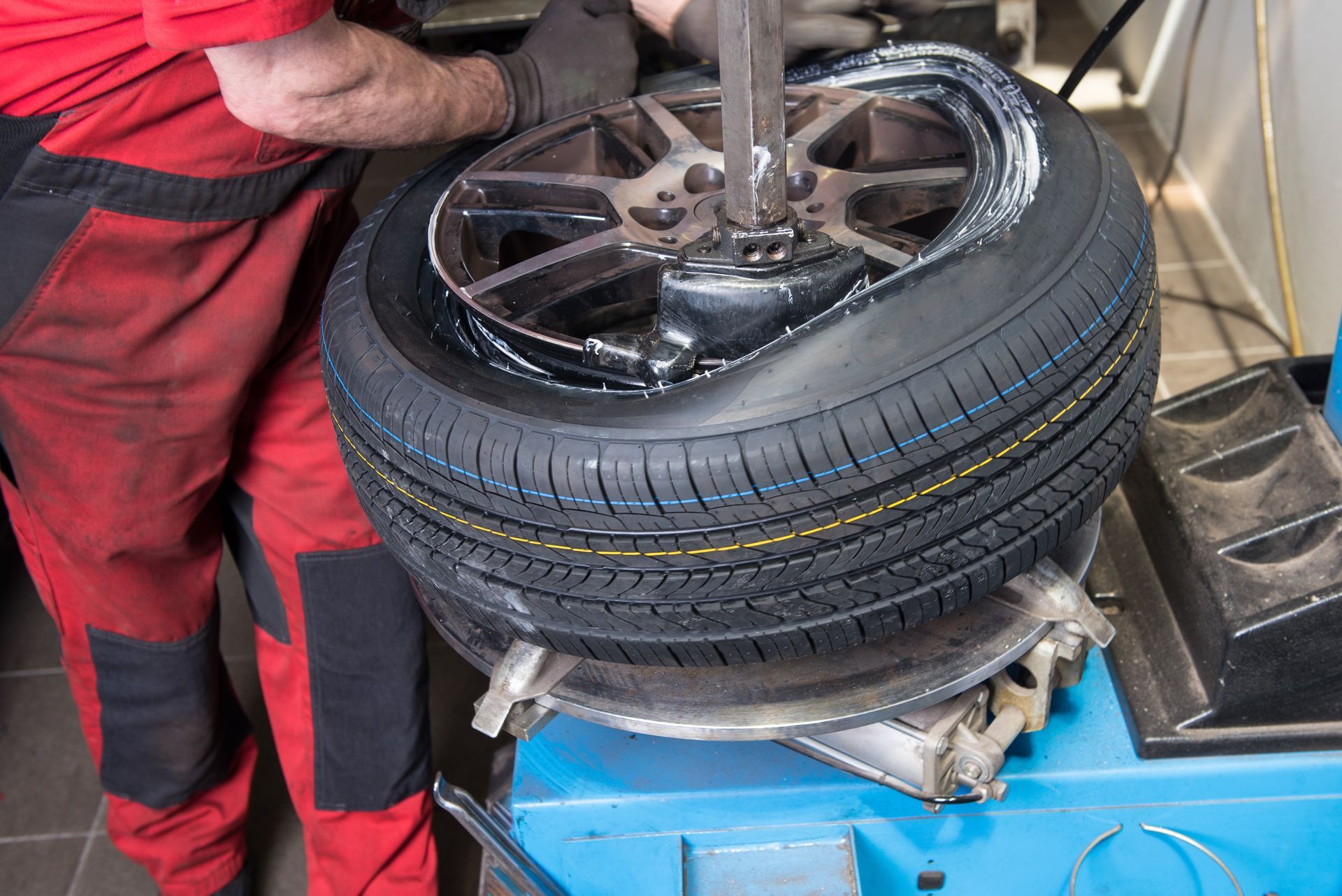 Un mécanicien change le pneu crevé d'une roue de voiture à l'aide d'une machine à pneus dans un garage.