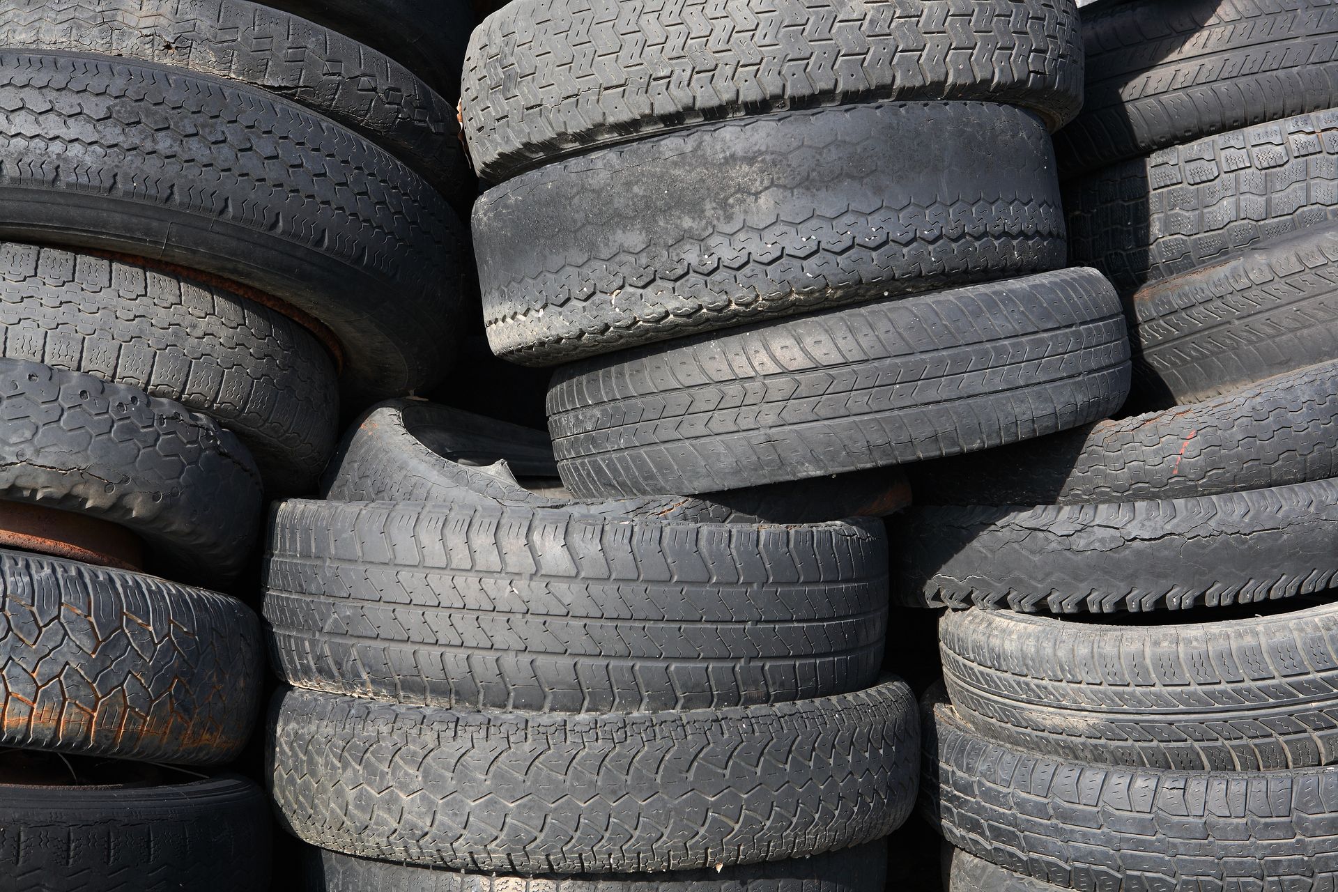 Un tas de pneus noirs usés, empilés pêle-mêle, probablement en vue de leur recyclage.