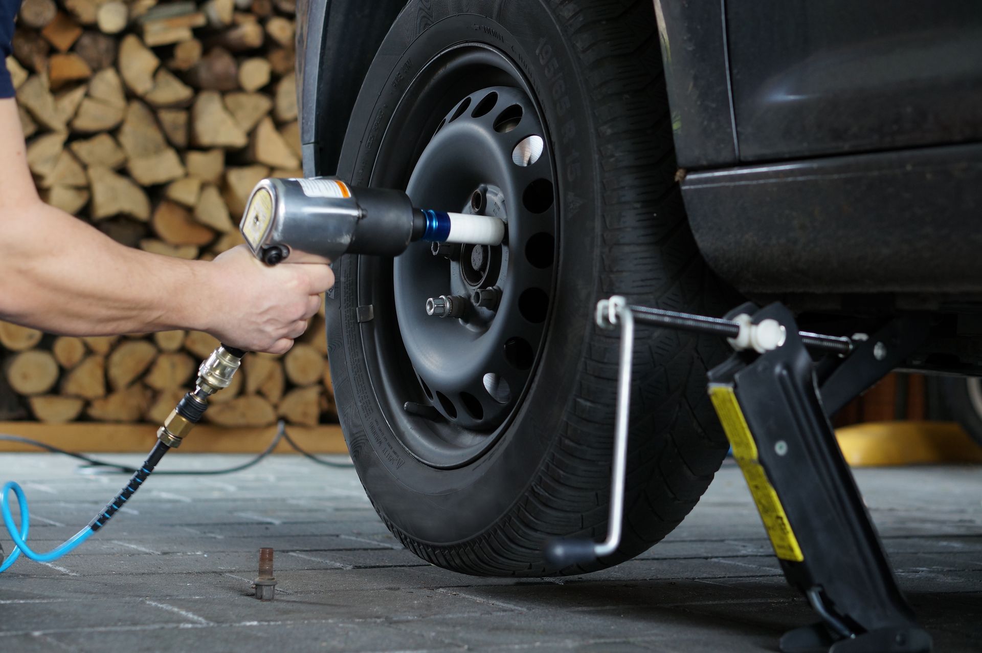 Une personne utilise une clé à choc pneumatique pour retirer les écrous d'un pneu de voiture.