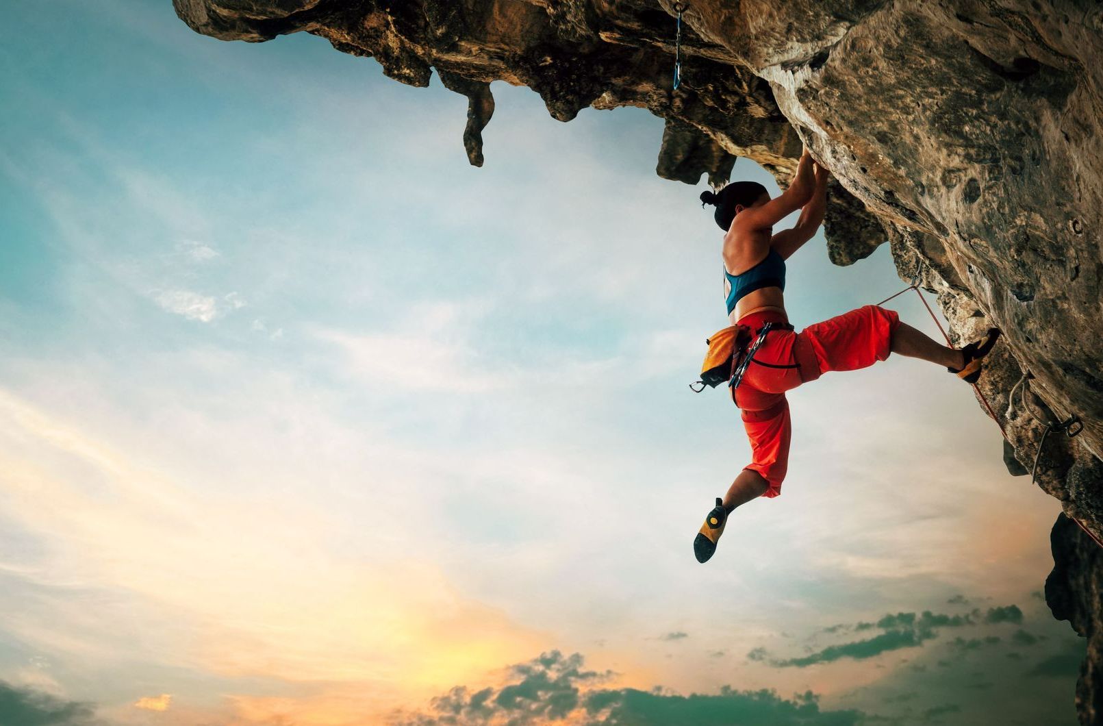 Une femme escalade une falaise.