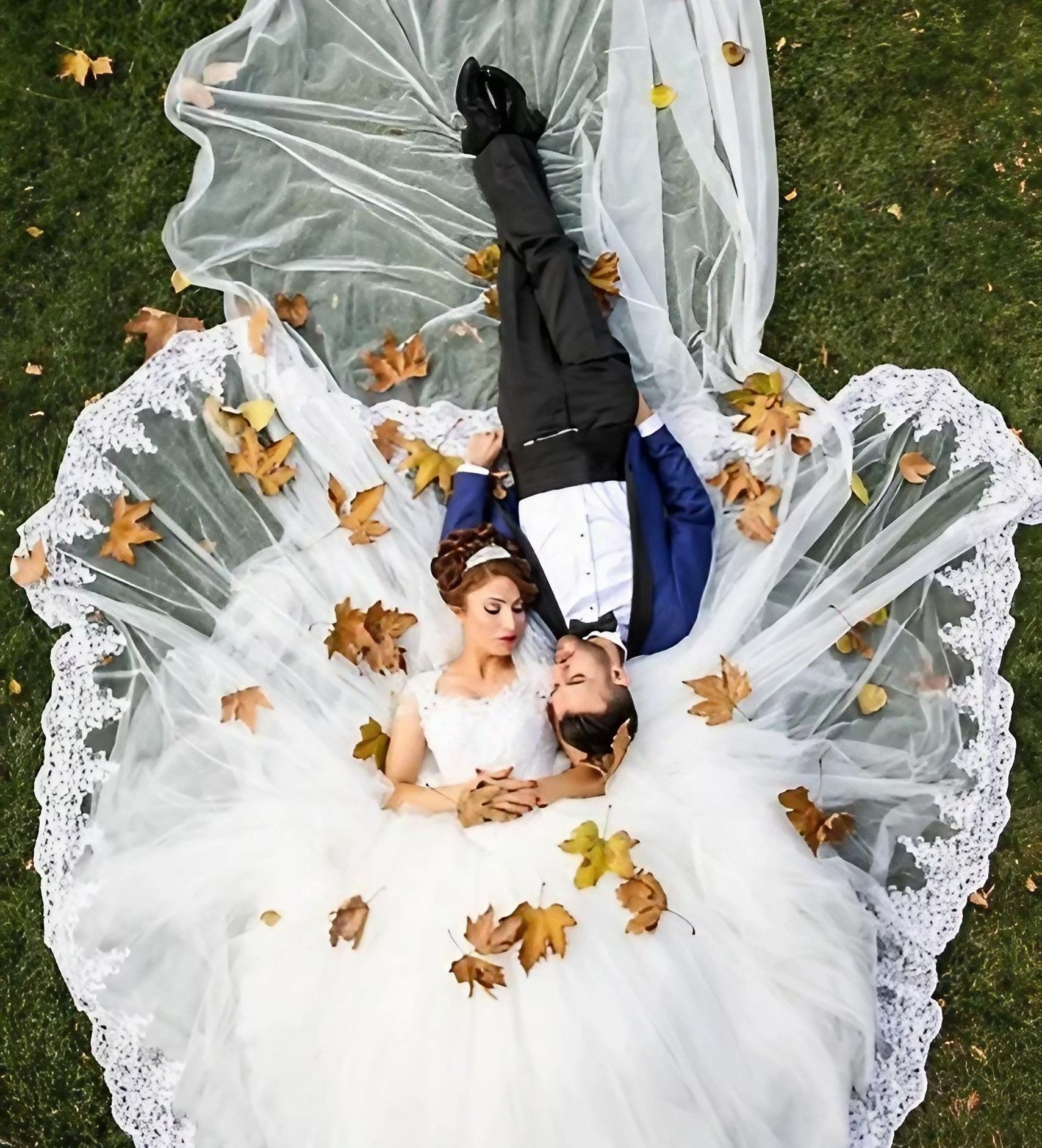Un couple de mariés allongés sur l'herbe.