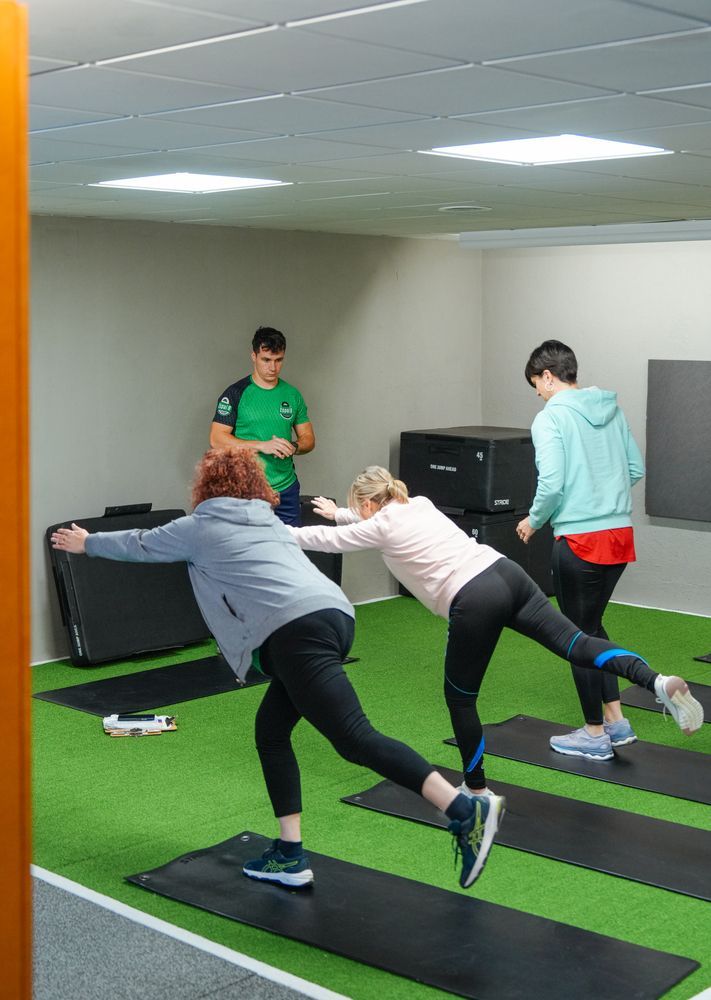 Un grupo de personas está haciendo ejercicios en colchonetas de yoga en un gimnasio.