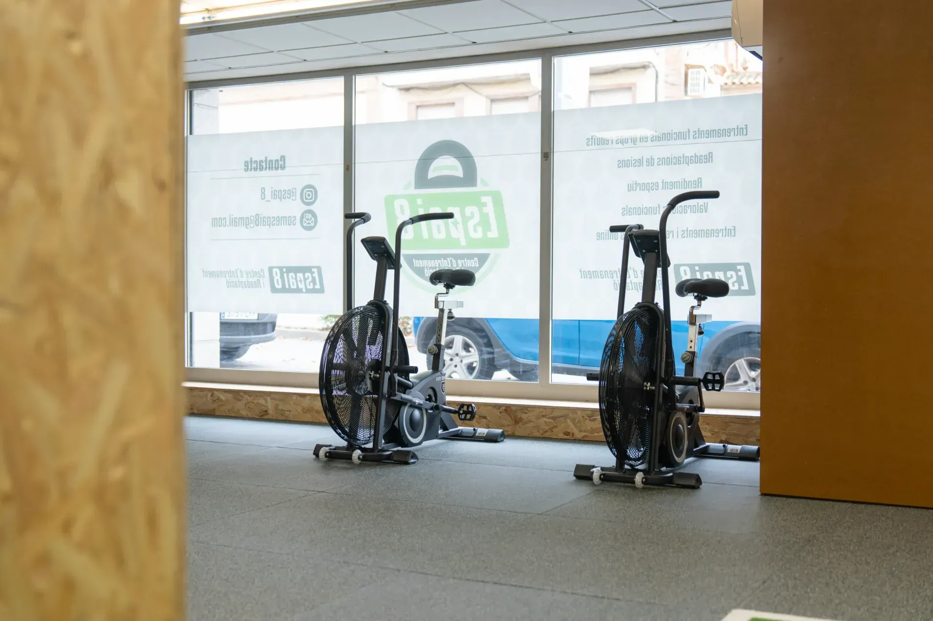 Dos bicicletas estáticas están sentadas en un gimnasio al lado de una ventana.