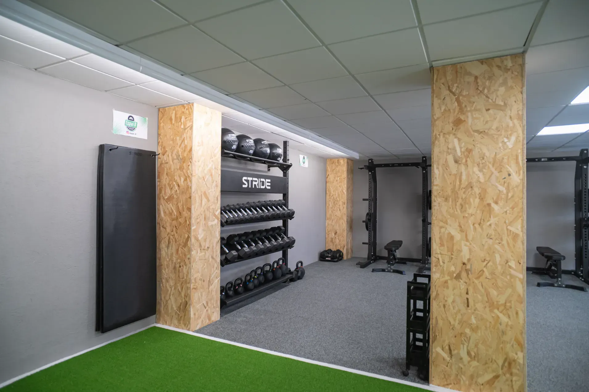 Un gimnasio con mucho equipamiento y alfombra verde.