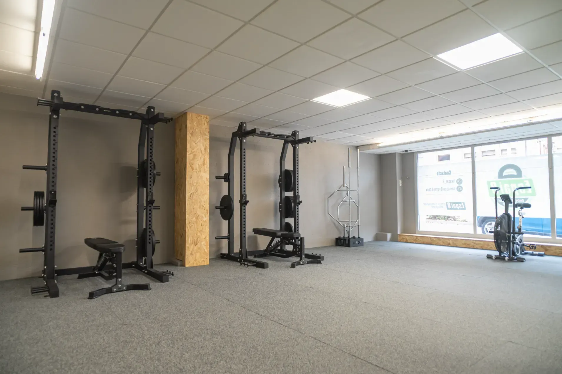 Un gimnasio con muchos equipos de ejercicio y muchas ventanas.