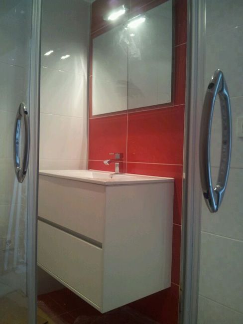Un baño con azulejos rojos, lavabo y espejo.