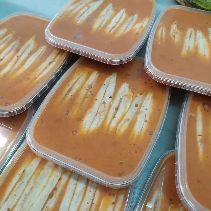 Un montón de recipientes de plástico llenos de salsa y pan.