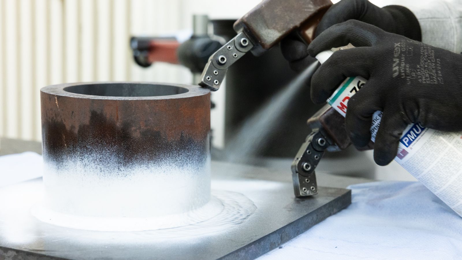 Ein Mann sprüht aus einer Spraydose auf ein Stück Metall.