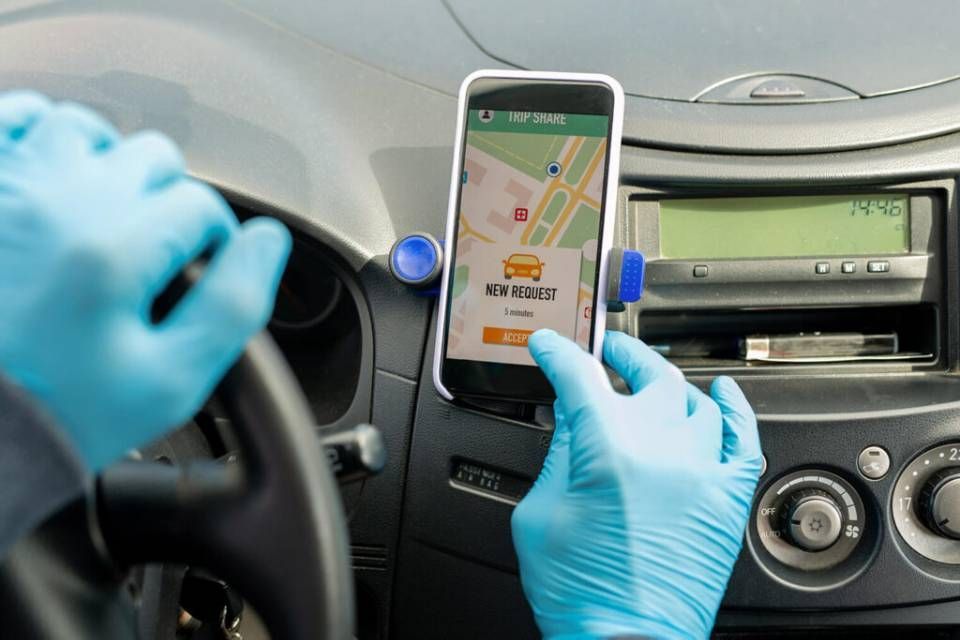 Behandschuhte Hände bedienen eine Smartphone-GPS-Halterung im Armaturenbrett eines Autos.