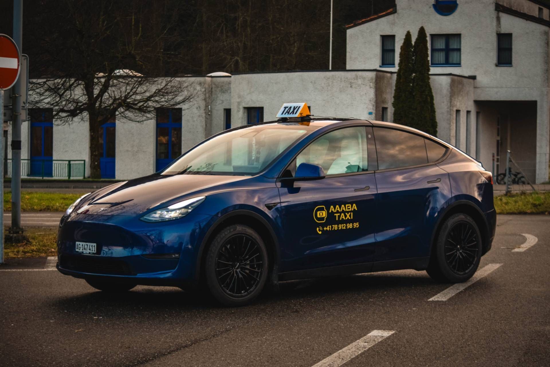 Ein blaues Taxi parkte in der Abenddämmerung vor Gebäuden auf der Strasse.