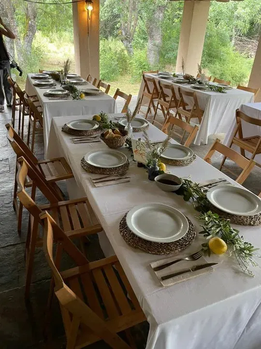 Una mesa larga con platos, sillas y utensilios sobre ella.