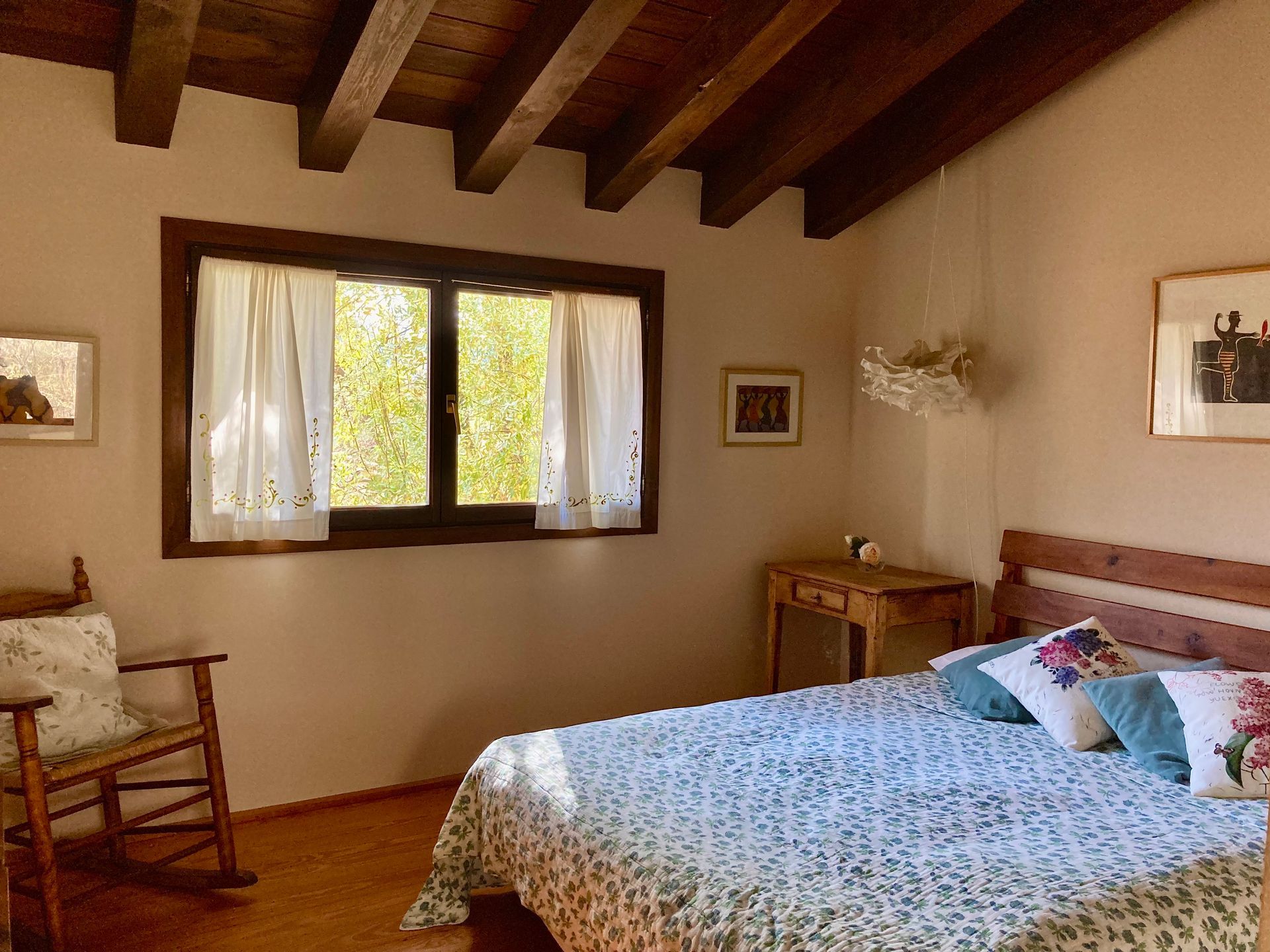 Un dormitorio con cama, silla, escritorio y ventana.