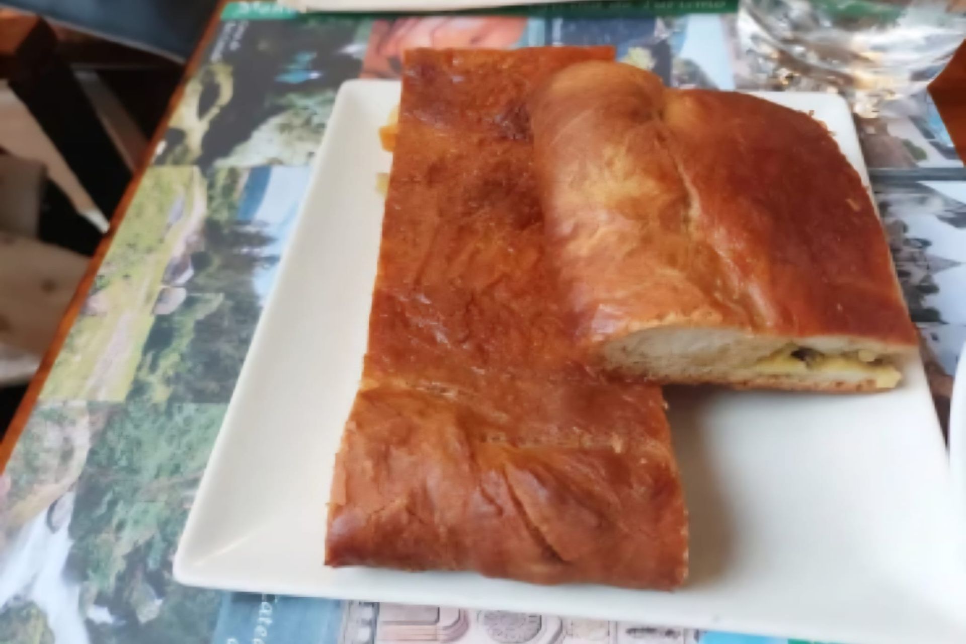 Dos rebanadas de hojaldre dorado sobre un plato blanco. Una rebanada está cortada para dejar al descubierto el relleno.