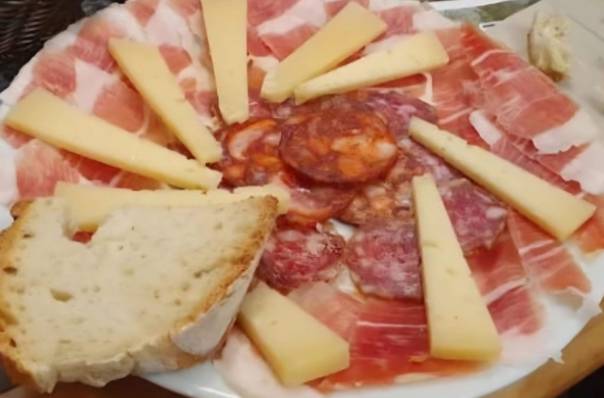 Tabla de embutidos con fiambres, cuñas de queso y pan.