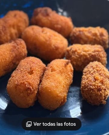 Croquetas fritas, doradas y de forma ovalada, dispuestas en un plato azul.
