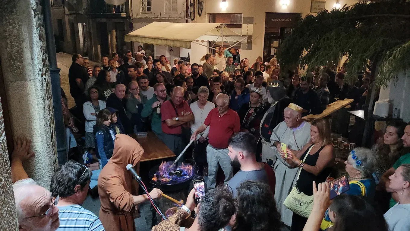 Gran multitud en un evento al aire libre con un artista cerca de una fogata, posiblemente en un festival.