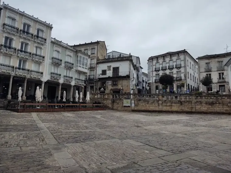 Una plaza empedrada rodeada de edificios blancos. Cielo nublado.