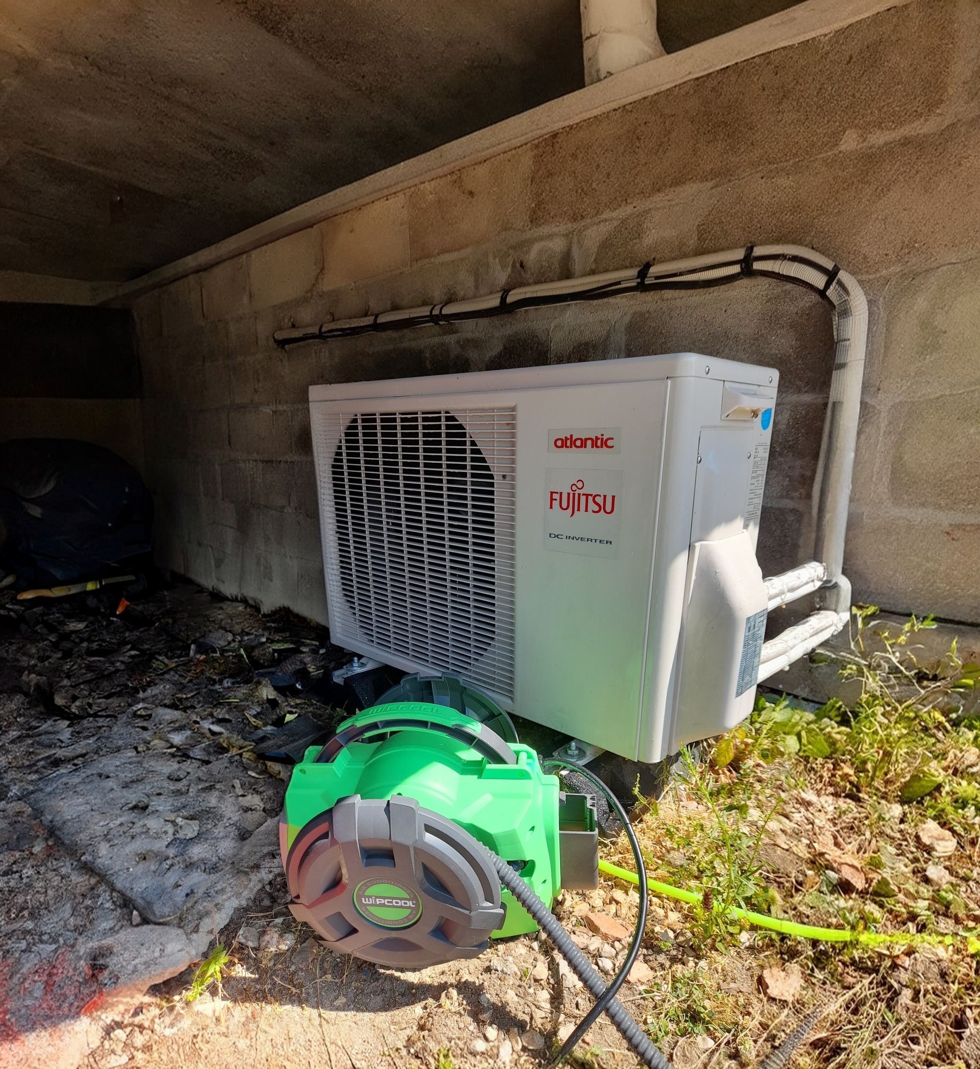 Un technicien ajuste un climatiseur mural sur un mur en briques