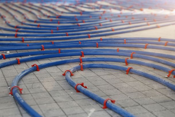 Des tuyaux bleus courbés avec des marqueurs rouges sont disposés sur un sol carrelé dans une installation abstraite
