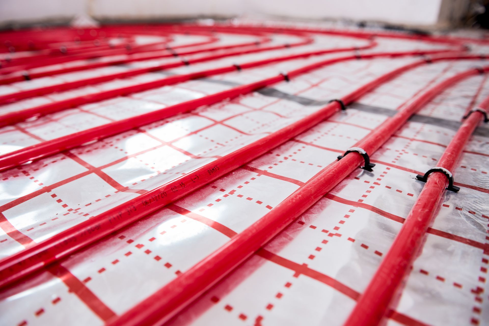 Tuyaux de chauffage au sol rouges posés sur des panneaux d'isolation blancs