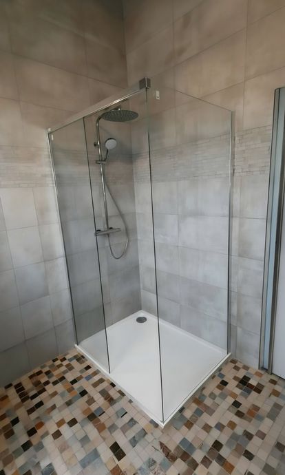 Petite salle de bains avec meuble lavabo blanc, miroir, paroi de douche foncée et receveur de douche à l'italienne.