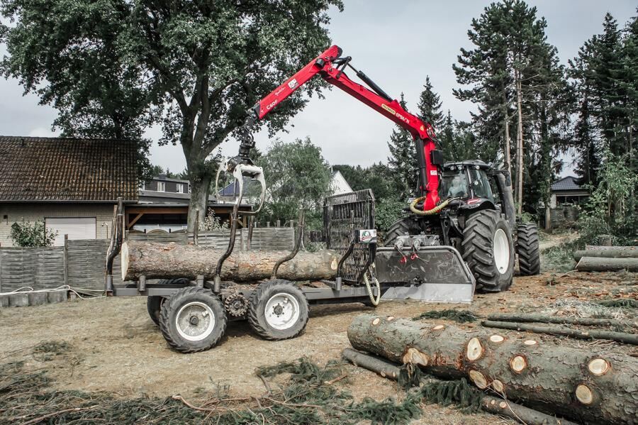 Ein Traktor zieht einen Anhänger voller Baumstämme.