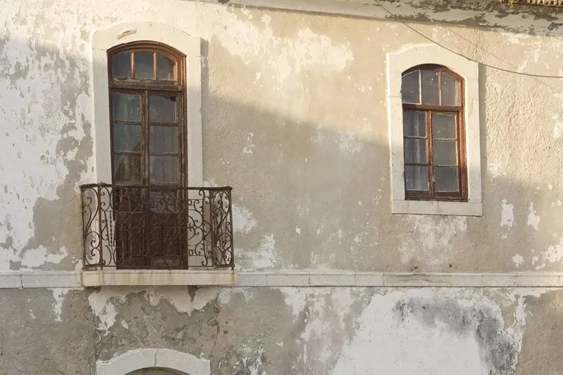 Um prédio antigo com uma varanda e duas janelas