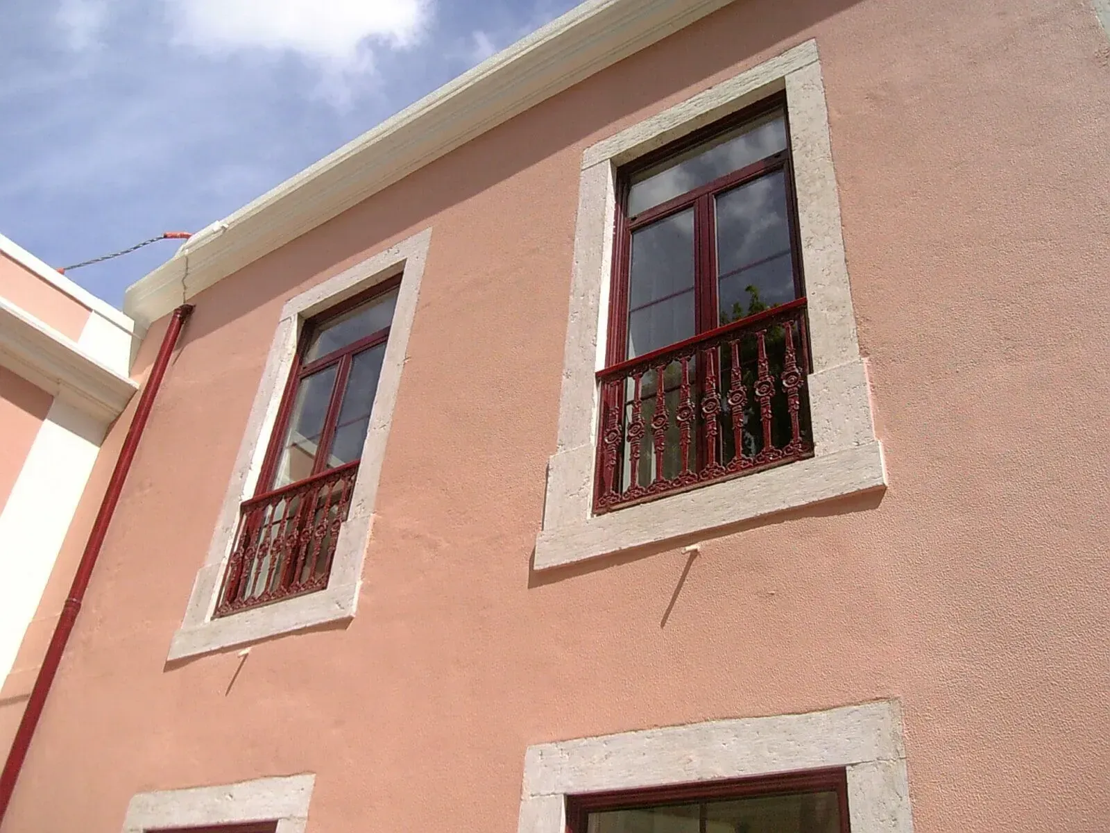 Um prédio rosa com duas janelas e uma varanda