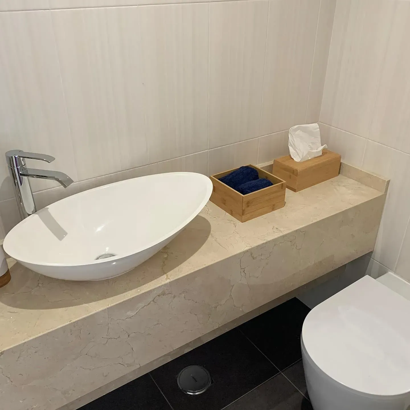 Um banheiro com pia, vaso sanitário e lenços de papel no balcão.