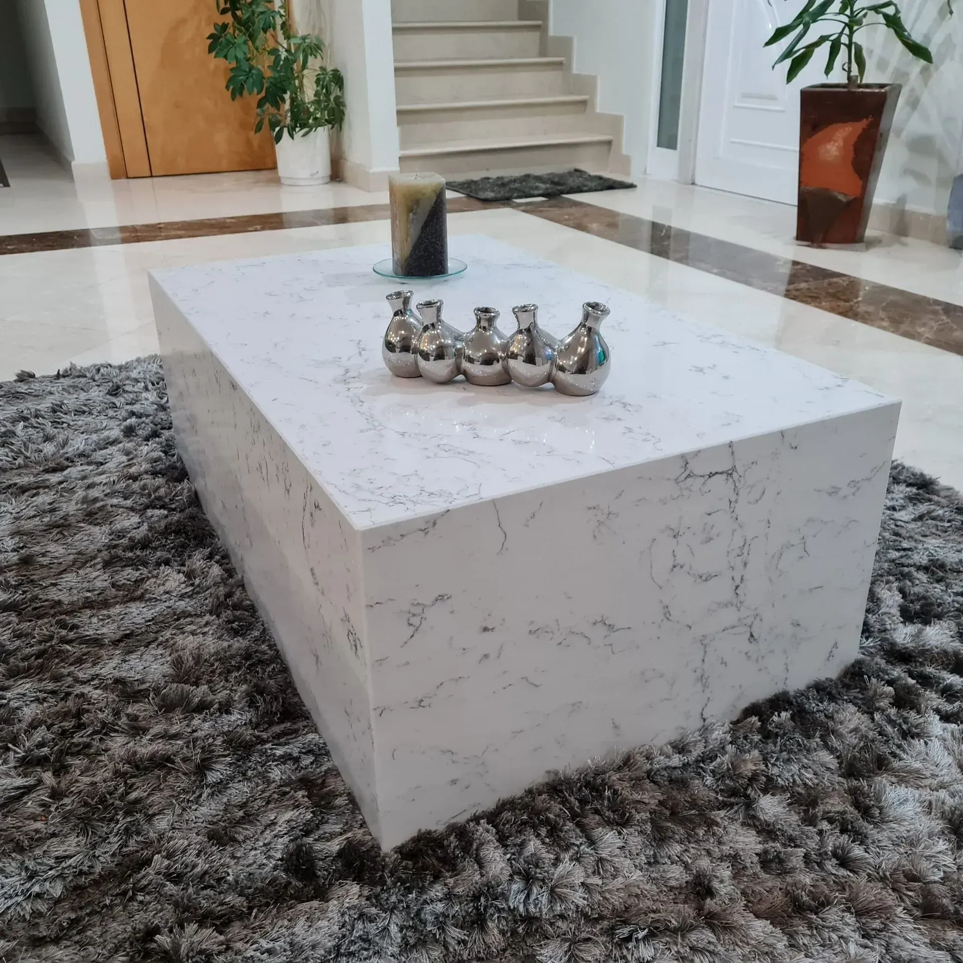 Uma mesa de centro de mármore branco está sobre um tapete em uma sala de estar.