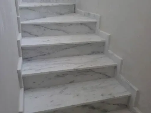 Um conjunto de escadas de mármore branco que levam ao segundo andar.