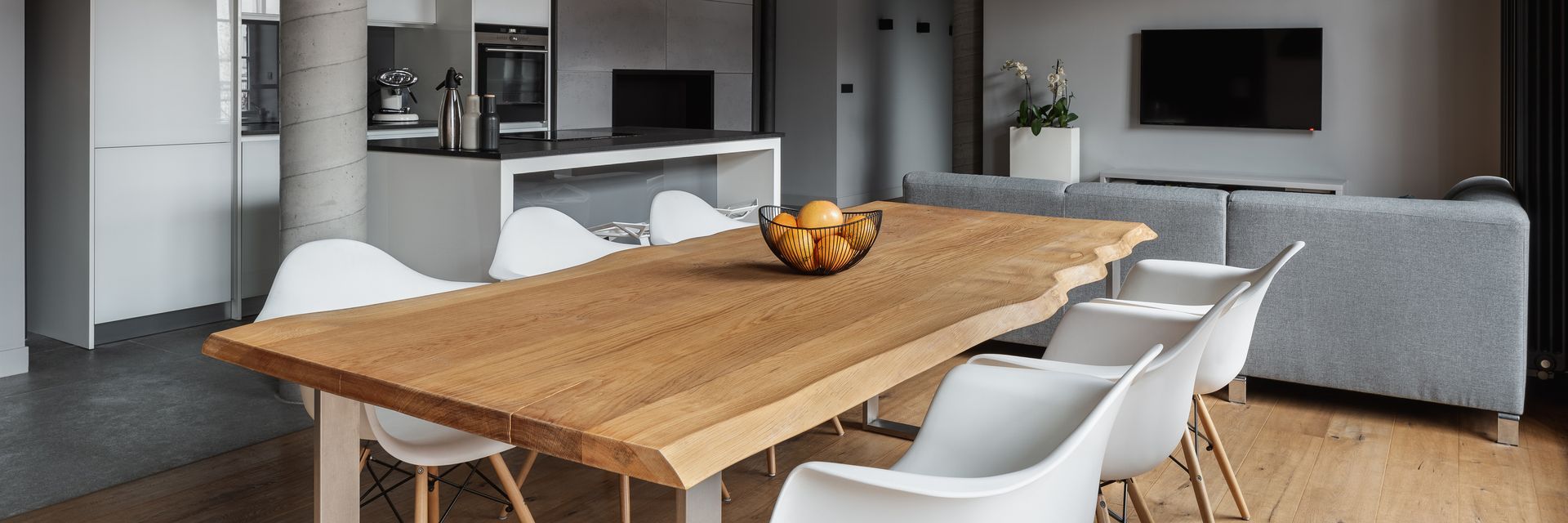Coin repas moderne avec une table en bois, des chaises et une corbeille de fruits dans un salon lumineux.