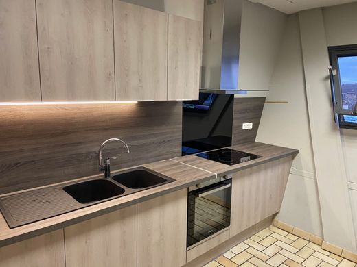 Cuisine moderne avec placards en bois clair, évier, crédence et four encastré.
