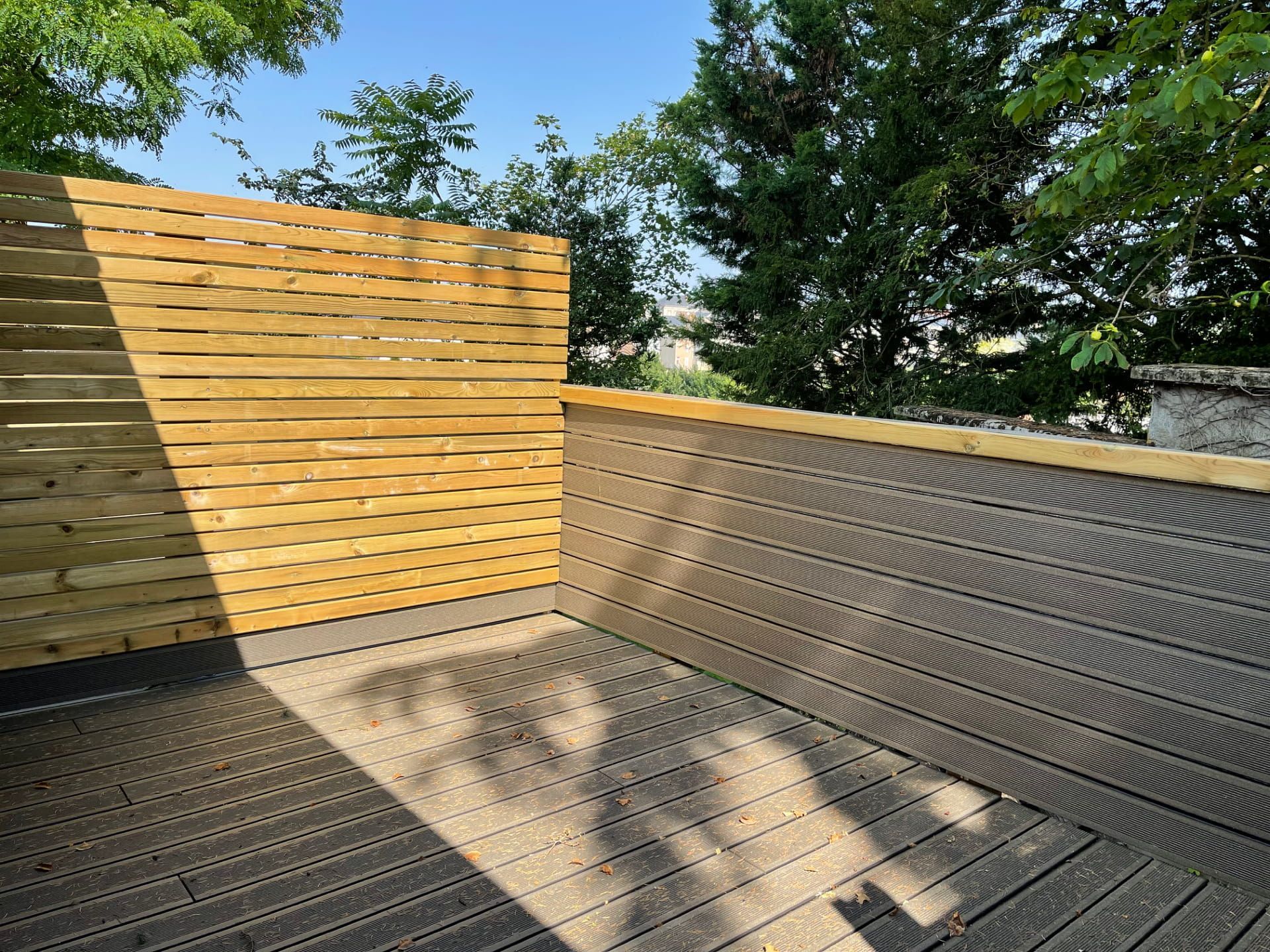 Terrasse en bois à l'arrière, avec plancher et panneaux de clôture à claire-voie.