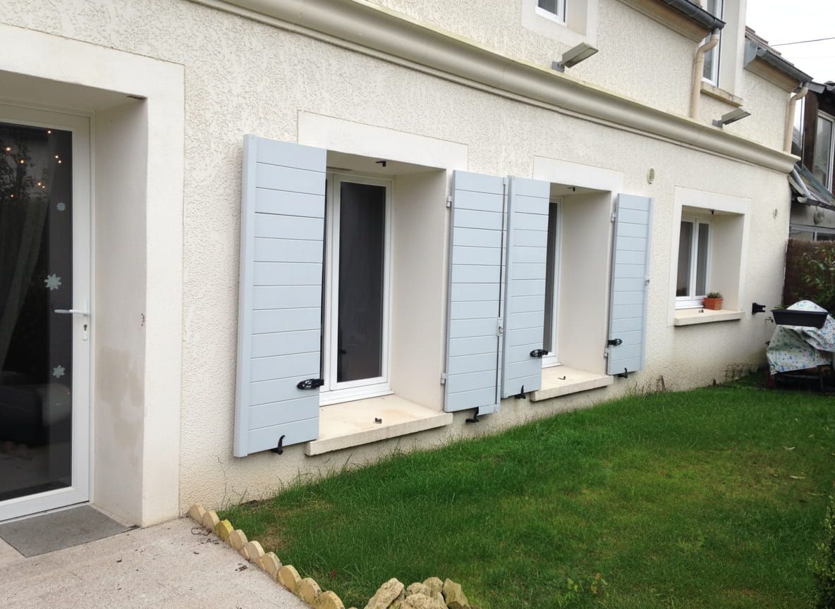 Extérieur de la maison avec volets, murs et pelouse.